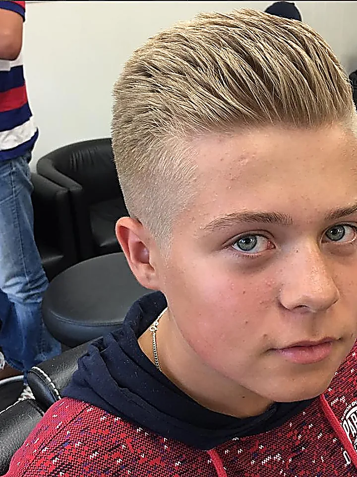 Blond herrklippning med uppåtstylad topp och fade